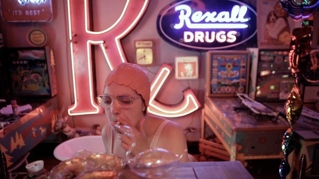 Une femme porte des lunettes, fume et porte un bonnet de bain sur la tête.