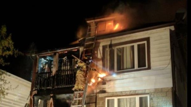 Un pompier sur une échelle devant le second étage d'un logement en flammes. Un pompier sur une échelle devant le second étage d'un logement en flammes.