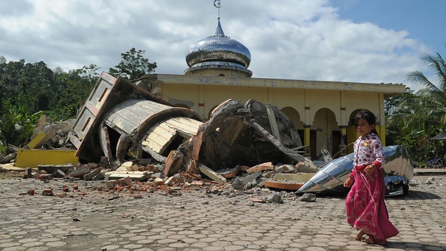 Une fillette se promène à côté des décombres d'un édifice effondré, à la suite d'un séisme en Indonésie, le 7 décembre 2016.