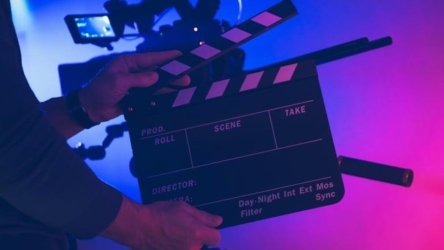 Une personne tient un claquoir pour indiquer le début du tournage d'une scène.