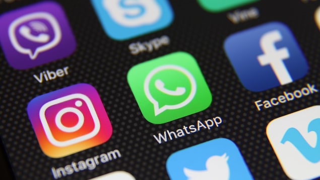 Une photo d'un écran de téléphone intelligent sur lequel sont affichés les icônes de différents réseaux sociaux. Ceux d'Instagram, de WhatsApp et de Facebook sont mis en évidence au centre.