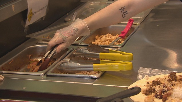 Un jeune employé prend de la nourriture sur un comptoir.