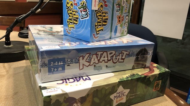 Trois jeux de société sont empilés sur une table.