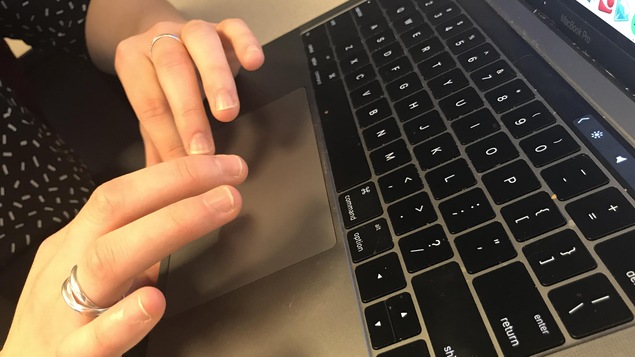 Des mains manipulent un ordinateur portable.