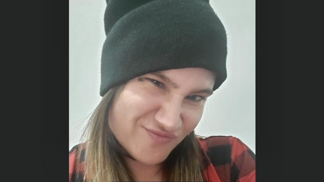 Photographie de la page Facebook de l'agresseuse. Elle porte une tuque noire et une chemise à carreaux.