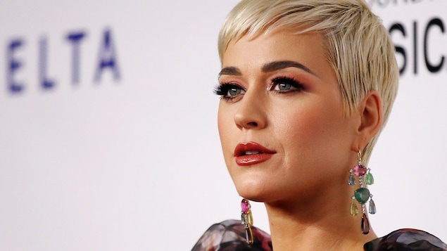 Katy Perry porte des cheveux blonds courts et des grosses boucles d'oreilles.