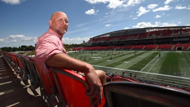 M. Evraire est assis dans le stade des Rouges et Noirs d'Ottawa. M. Evraire est assis dans le stade des Rouges et Noirs d'Ottawa.