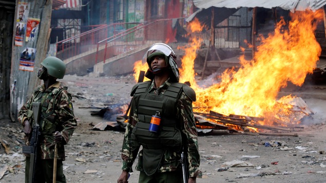 Des policiers postés devant un feu allumé par des manifestants à Nairobi Des policiers postés devant un feu allumé par des manifestants à Nairobi
