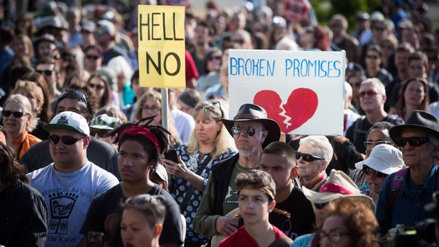 Des gens rassemblés tiennent des pancartes de protestation.