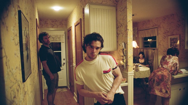 Un homme regarde la caméra dans un décor vieillot.