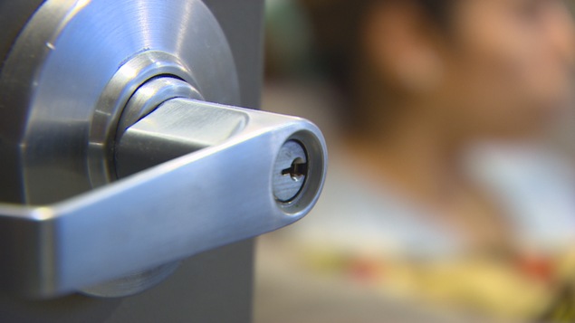 Une femme se tient derrière une porte close