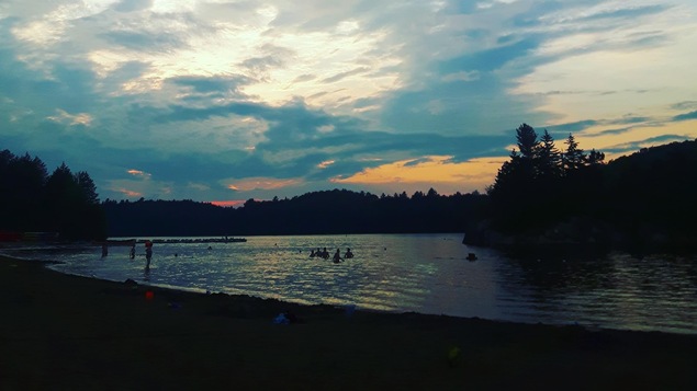 La plage du lac Stukely a été fermée temporairement après des tests effectués le 3 juillet. Des baigneurs se baignent au coucher du soleil.