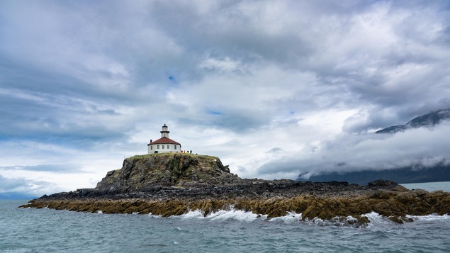 Le phare d'Eldred Rock se dresse en haut de son rocher dans le canal Lynn avec des montagnes dans le fond et l'océan, en Alaska, juillet 2022.