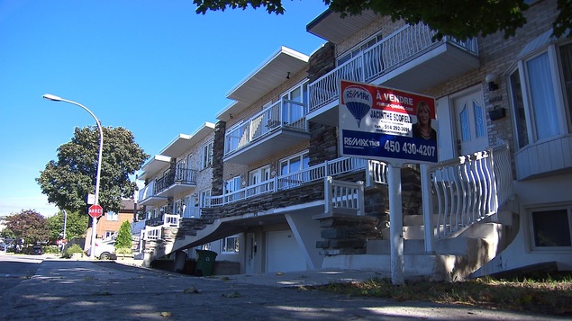 Une pancarte d'un courtier immobilier près d'une maison à vendre