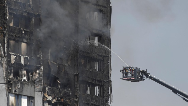 Des pompiers dirigent leur lance d'eau vers la tour à appartements lourdement endommagée par les flammes. Des pompiers dirigent leur lance d'eau vers la tour à appartements lourdement endommagée par les flammes.