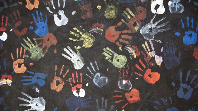 Des empreintes de mains colorées sur un tableau d'école.