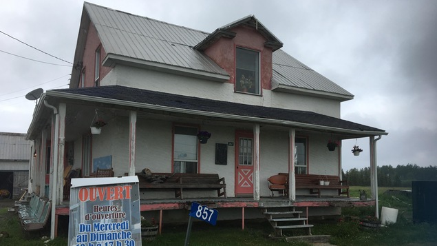Une maison vieillotte avec une affiche indiquant les heures d'ouverture et les tarifs de visite.