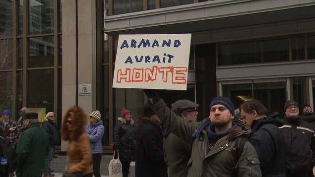 Un manifestant brandi une pancarte sur laquelle on peut lire : "Armand aurait honte." Un manifestant brandi une pancarte sur laquelle on peut lire : "Armand aurait honte."