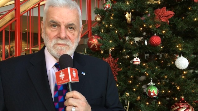 Marc Arnal devant un arbre de Noël et un escalier, à la Cité francophone d'Edmonton