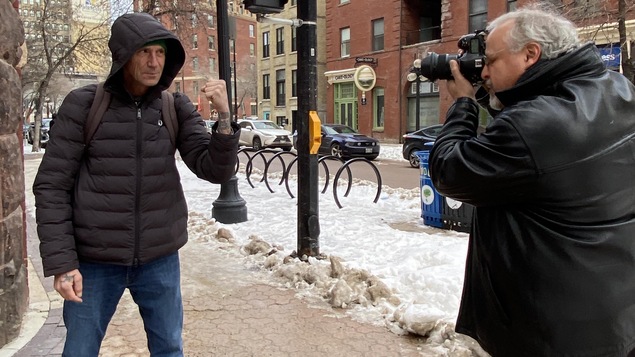 Un homme photographie un passant dans la rue alors qu'il fait un geste de boxe.