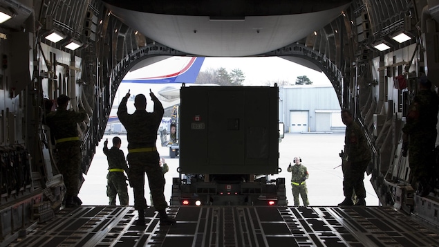 Des militaires chargent un conteneur dans un avion. Des militaires chargent un conteneur dans un avion.