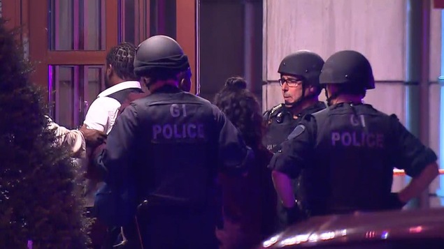 Trois policiers surveillent l'entrée de l'immeuble où l'homicide est survenu. Trois policiers surveillent l'entrée de l'immeuble où l'homicide est survenu.