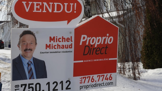 Une pancarte devant une résidence sur laquelle le nom et le portrait de Michel Michaud sont inscrits.