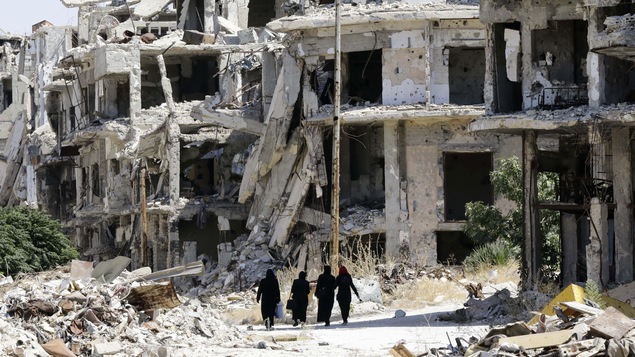 Des femmes syriennes se promènent entre des bâtiments détruits à Homs, en Syrie.
