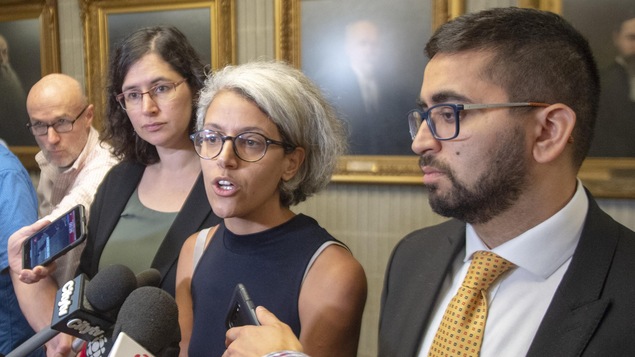 Les trois intervenants sont entourés de journalistes.