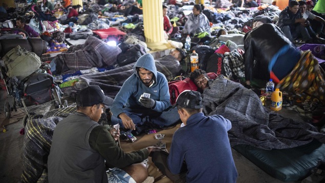 Des migrants dorment ou jouent aux cartes dans un refuge.