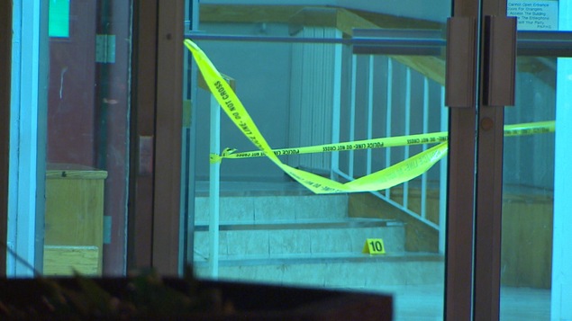 Banderole jaune de police derrière la porte d'entrée de l'immeuble.