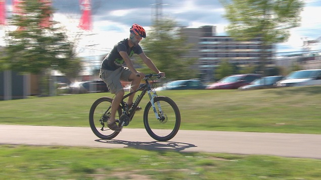 Un cycliste pédale sur le sentier riverain