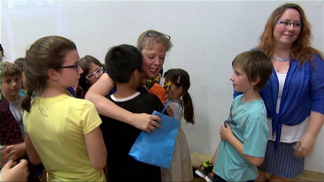 Des enfants enlacent leur enseignante en lui remettant des cadeaux,