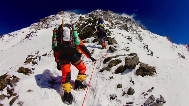 Des alpinistes encordés gravissent le flanc d'une montagne enneigée.