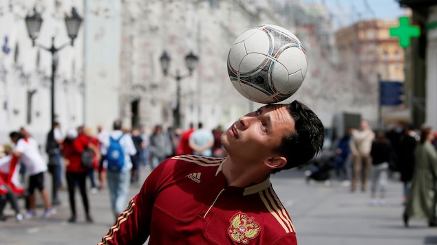 Un homme vêtu du maillot de la Russie s'exerce avec un ballon de soccer dans les rues de Moscou.