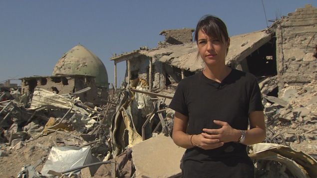 La correspondante Marie-Ève Bédard devant des ruines de Mossoul, en Irak