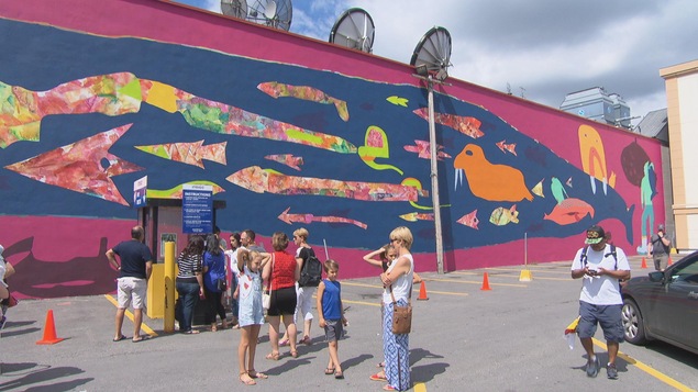 Des gens dans un stationnement, devant une murale Des gens dans un stationnement, devant une murale