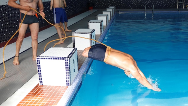 Un afghan amputé des deux jambes pratique la natation. Attaché à une corde tenu par un autre homme, il plonge à l'eau. Un afghan amputé des deux jambes pratique la natation. Attaché à une corde tenu par un autre homme, il plonge à l'eau.