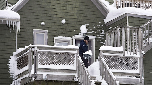 Un homme déneige son balcon et ses escaliers à Dartmouth en Nouvelle-Écosse le 14 février 2017.