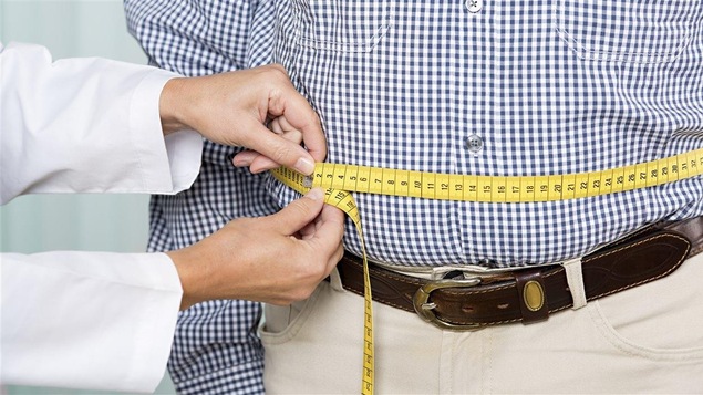 Un médecin mesure le tour de taille d'un homme.