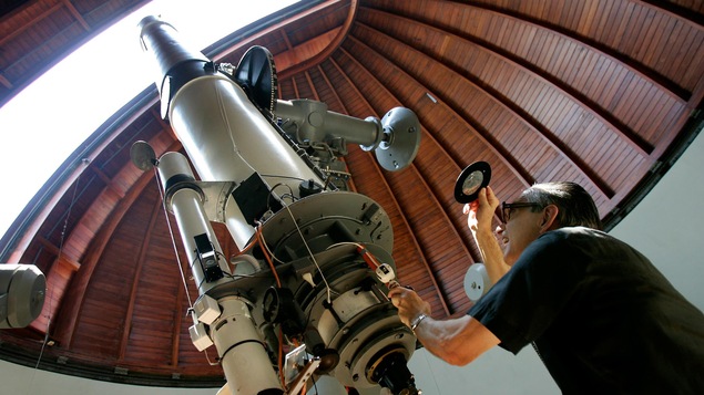 Un prêtre regardant dans la lentille d'un télescope Un prêtre regardant dans la lentille d'un télescope