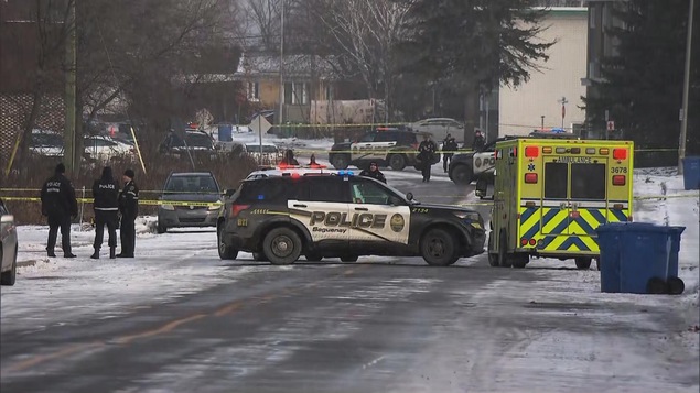 Plusieurs voitures de police et une ambulance sur une rue barrée.
