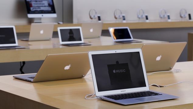 Plusieurs ordinateurs portables de la marque Apple sont disposés sur des tables.