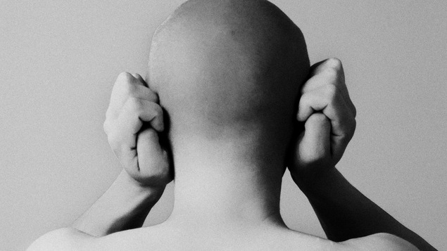 Une personne vue de dos couvre ses oreilles avec ses mains. Une personne vue de dos couvre ses oreilles avec ses mains.