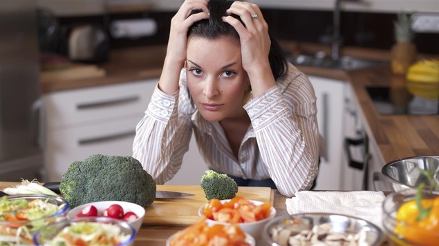 Une femme n'arrive pas à choisir entre des assiettes de légumes