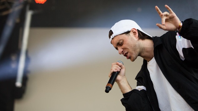 Le rappeur Loud pendant un concert, une main dans les airs.