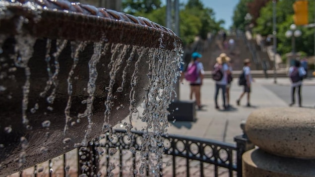 Une fontaine au centre-ville d'Ottawa en premier plan et des passants au second plan