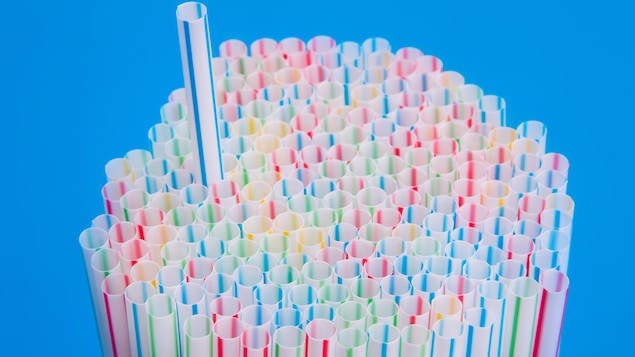 Une paille ressort d'une pile de pailles colorées.