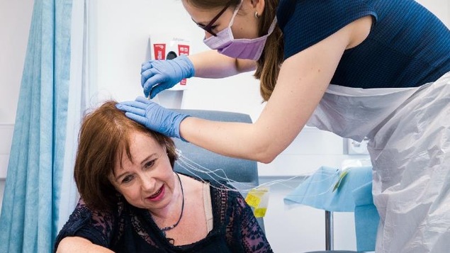 Une infirmière injecte le traitement dans un tube inséré dans le crane de la participante