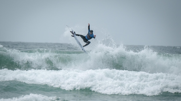 Peter Devries, champion canadien de surf 2019, est debout sur sa planche en haut d'une vague qui se brise à Tofino.